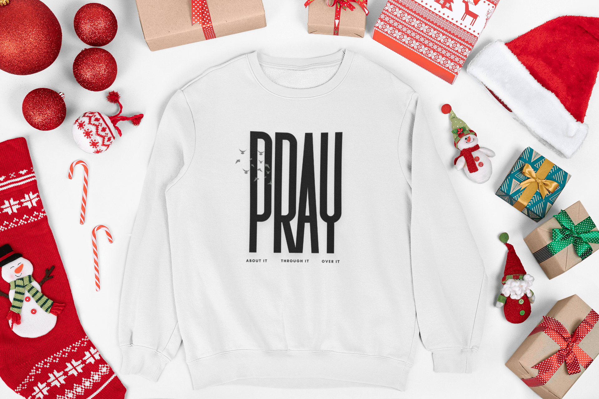White sweatshirt with 'PRAY' text surrounded by Christmas decorations on a white background