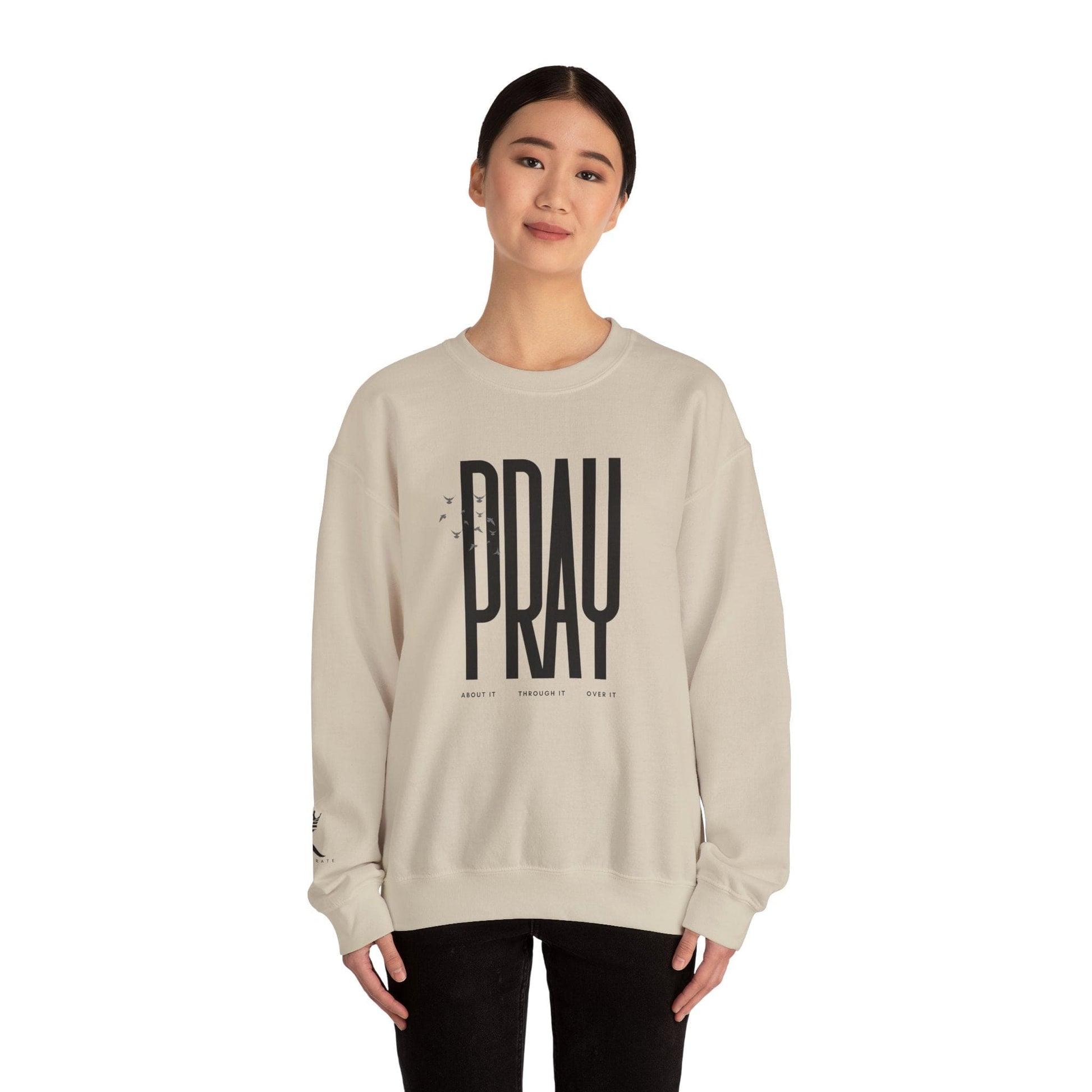 Woman wearing a sand sweatshirt with 'PRAY' printed on it against a white background