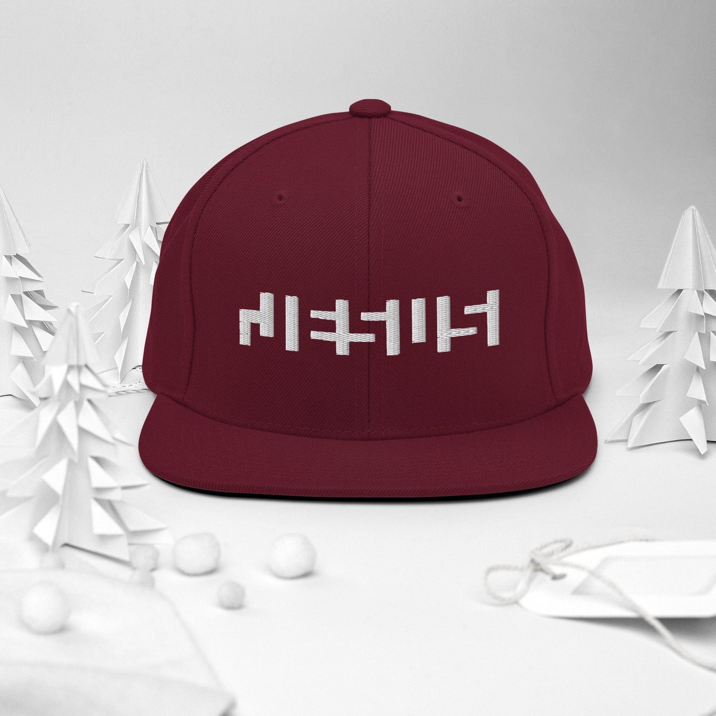 Maroon snapback with "Jesus" in white embroidery with background of christmas Decor